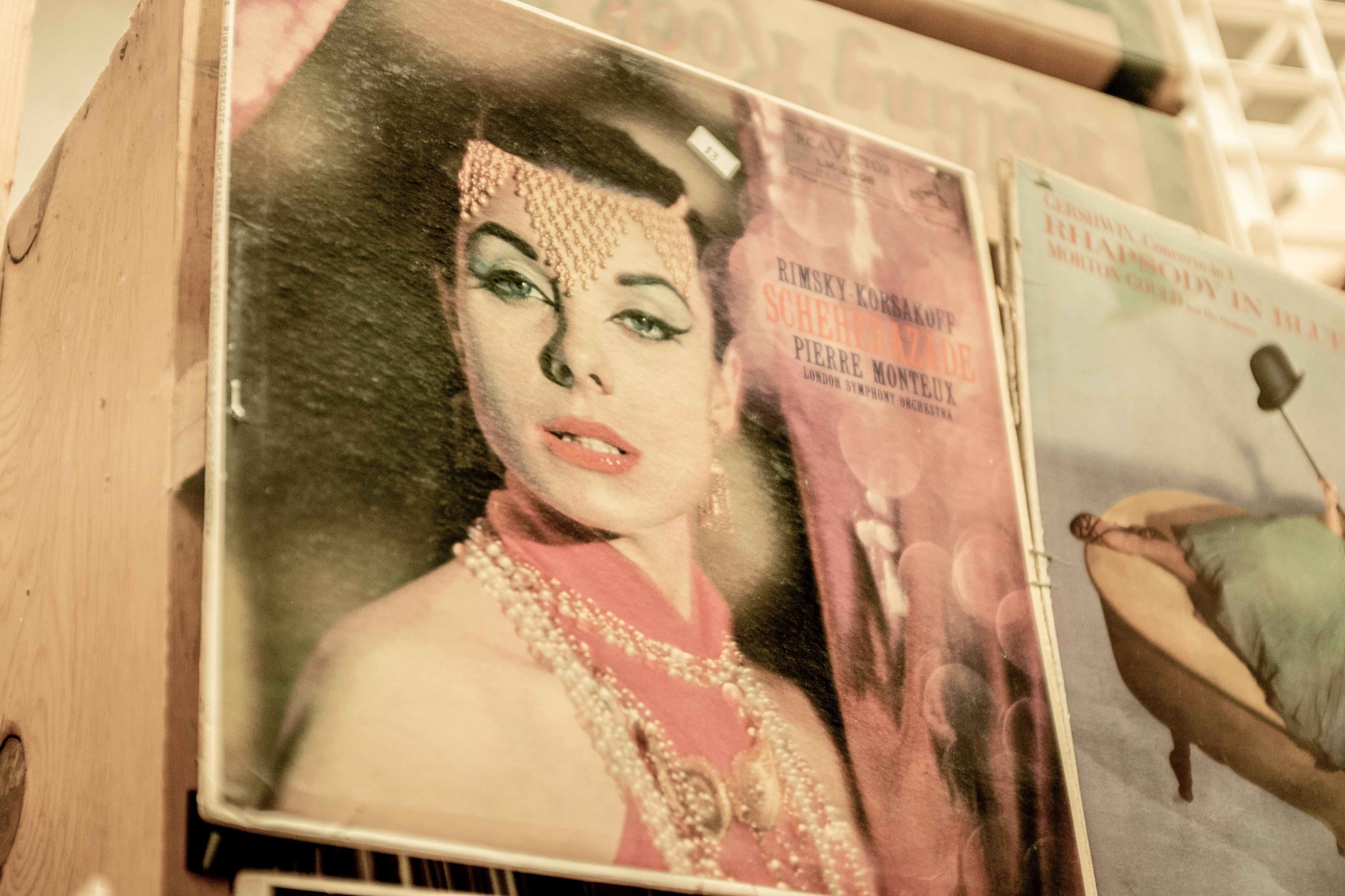 A poster of a woman wearing makeup, a pink top and pink and gold accessories around her neck and forehead.