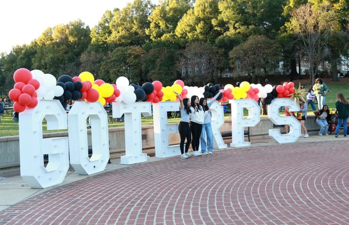 Students take a photo with the giant \"go terps\" sign