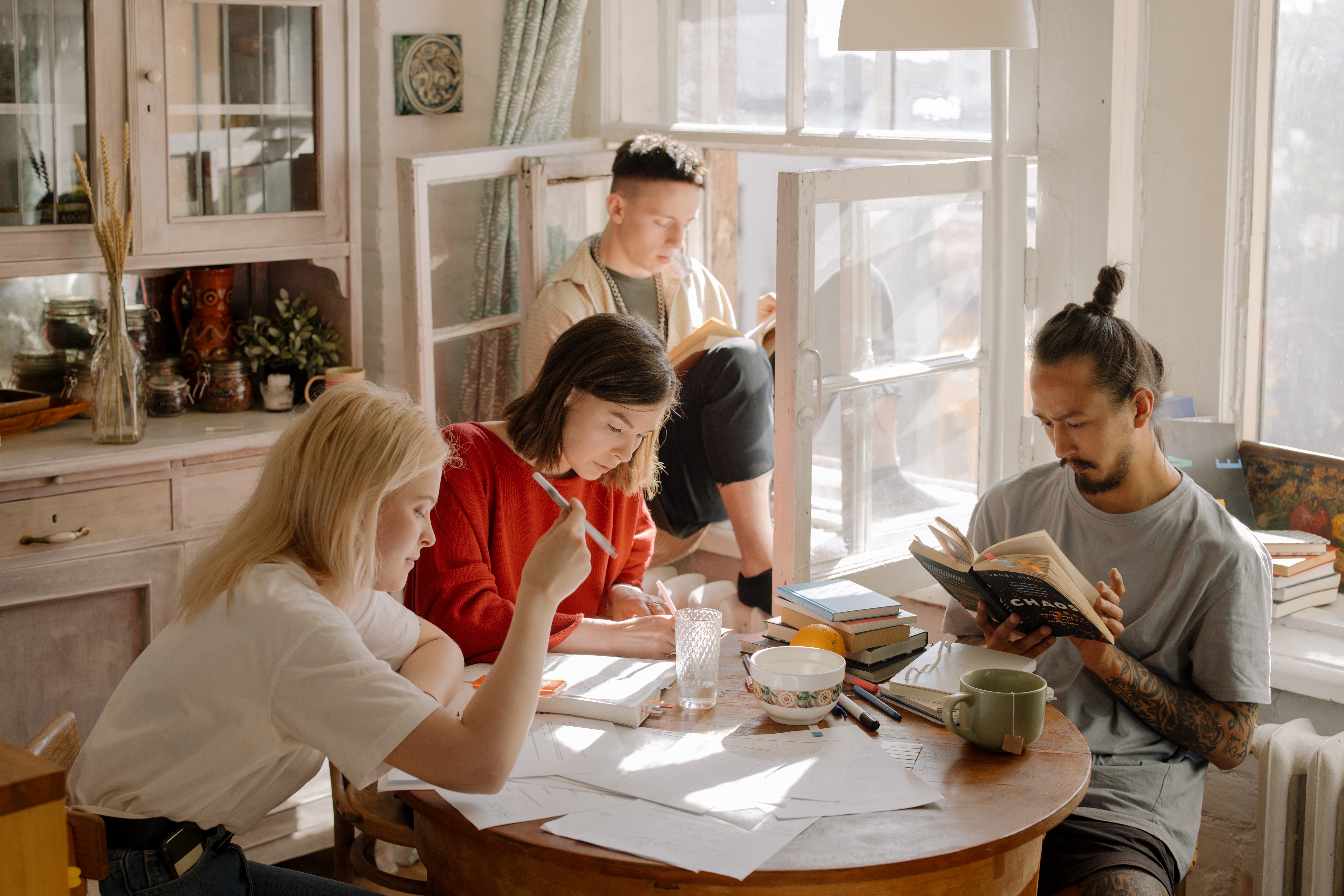 Folks sitting around a kitchen table studying and reading