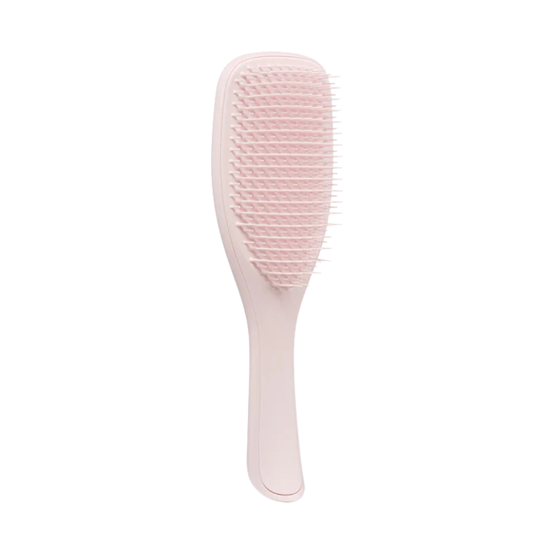 A pink detangling hairbrush with a curved handle and flexible bristles against a white background, conveying a soft, modern aesthetic.