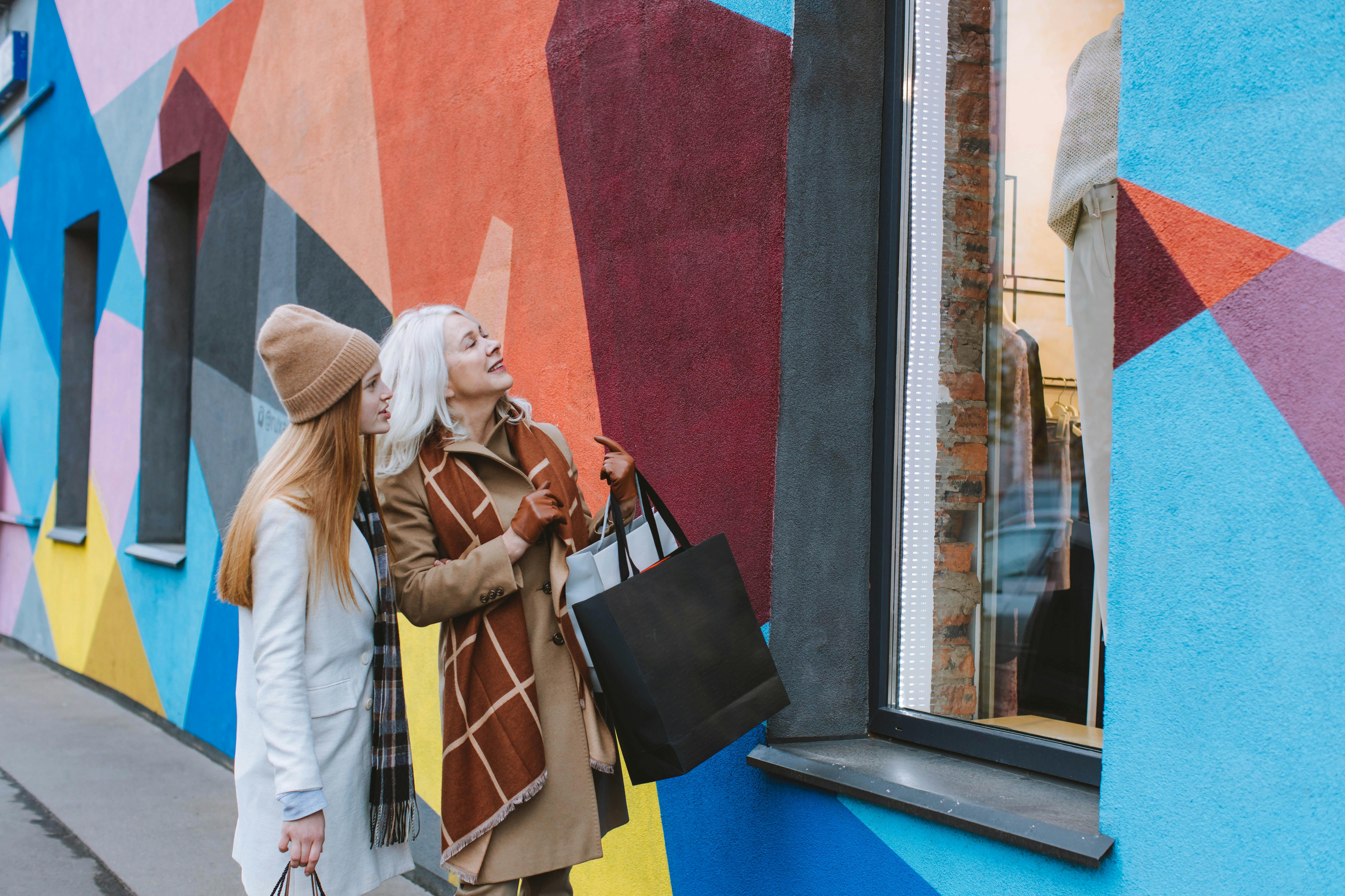 two women window shopping outside of a colourful storefront