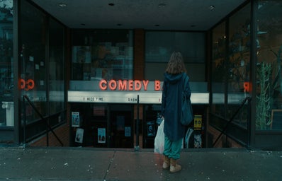 a woman standing in front of a comedy club