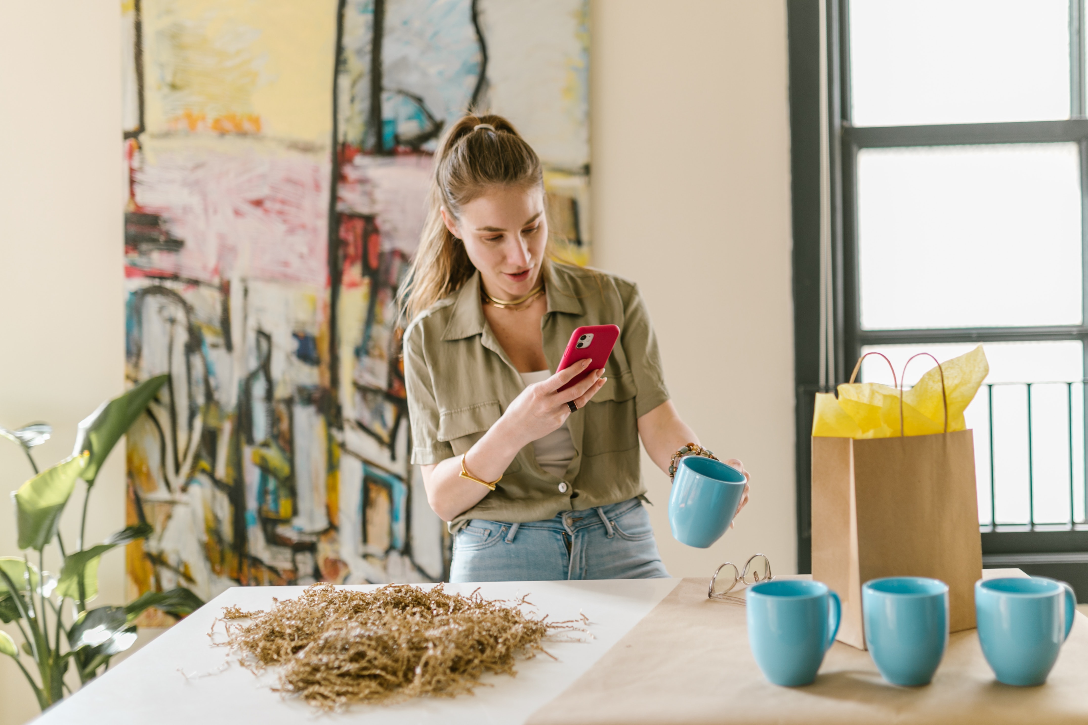 A woman standing over a desk while taking a picture of the materials on the table
