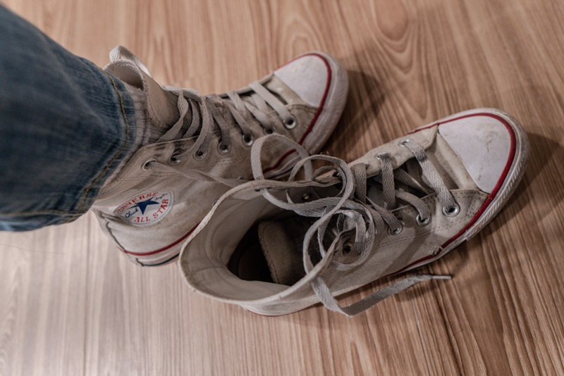 one foot in a high top white converse and the other out