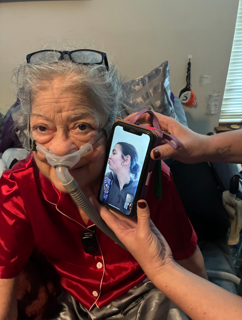 Granddaughter kissing grandmother on the cheek through a facetime call