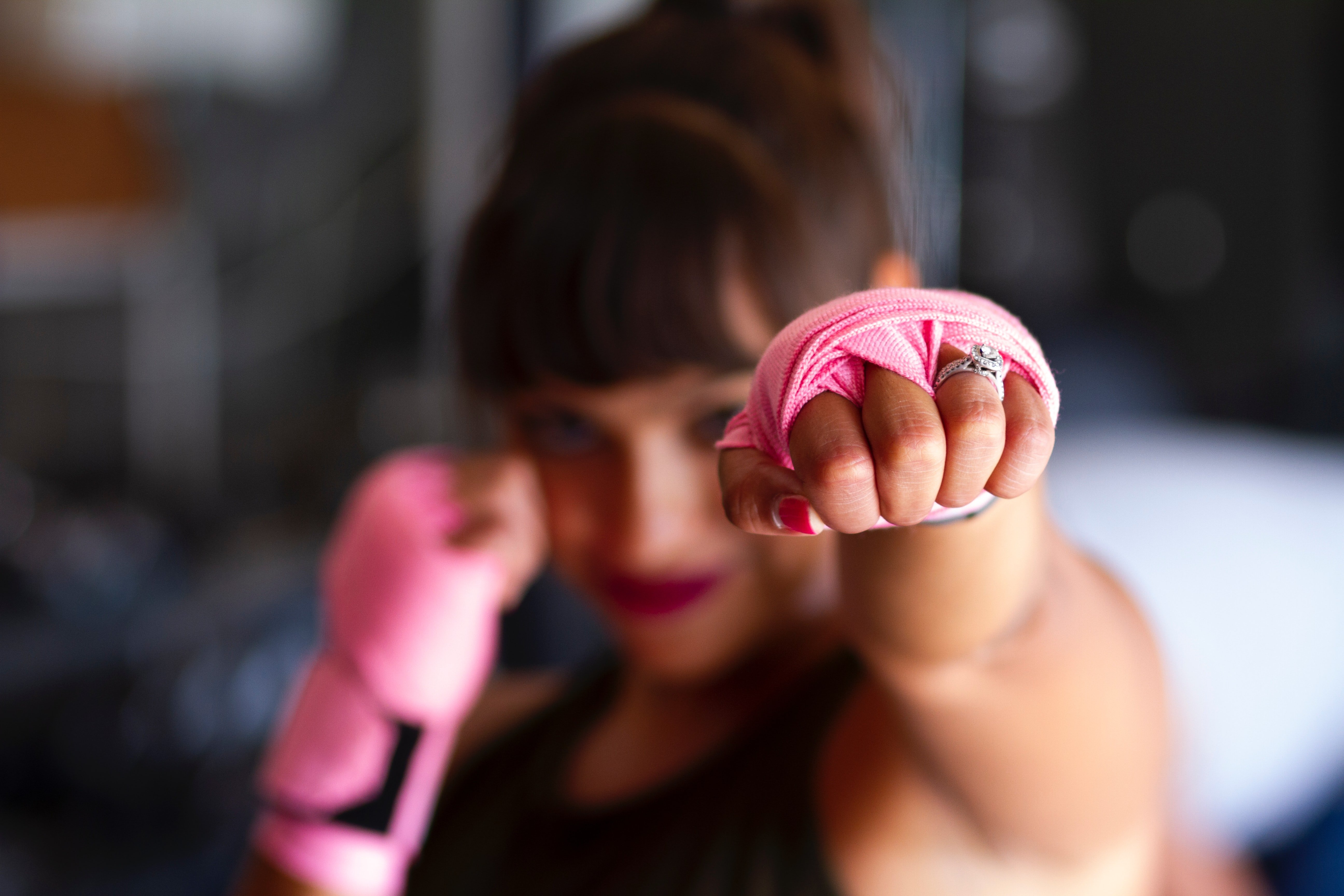 Blurred image a woman punching with pink wrist wraps on