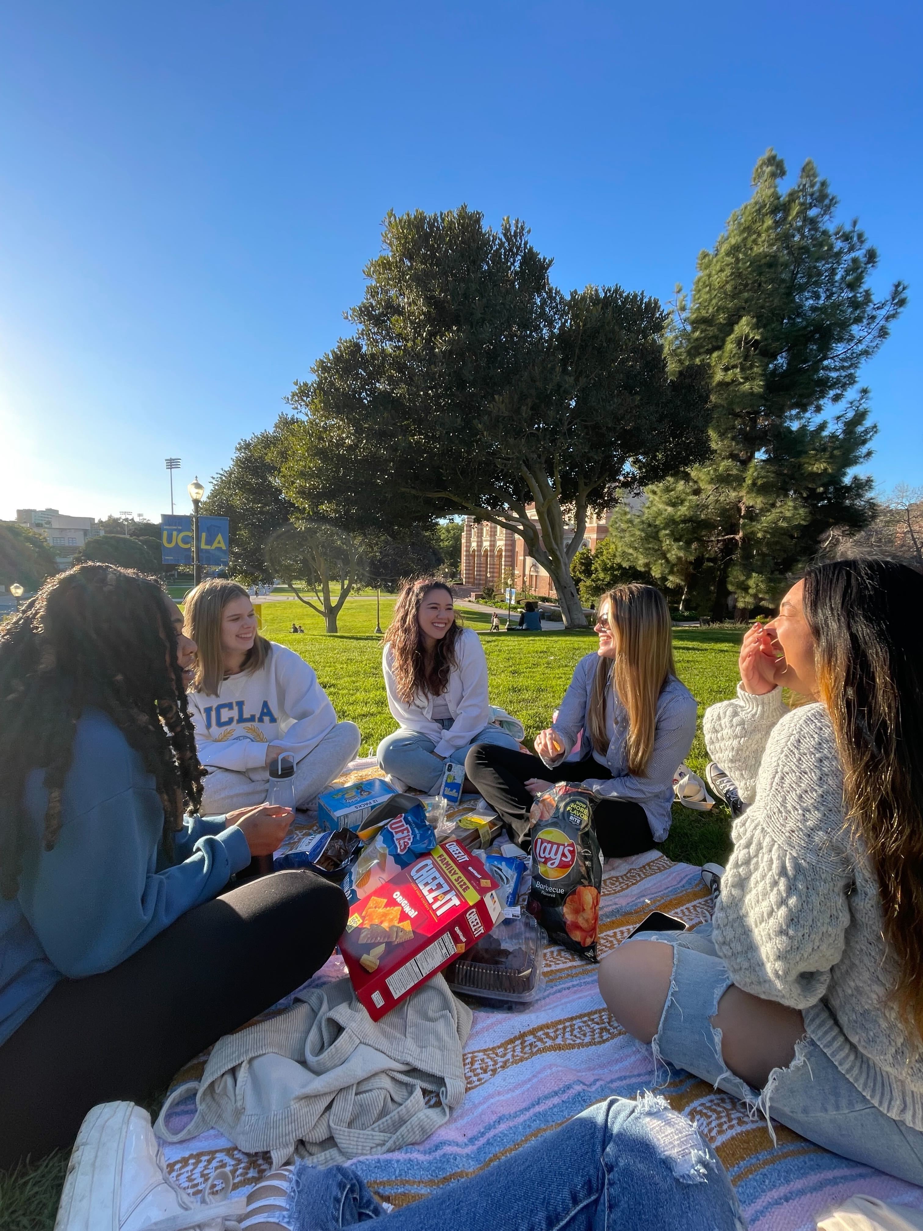 A group of girls have a picnic outside and laugh.