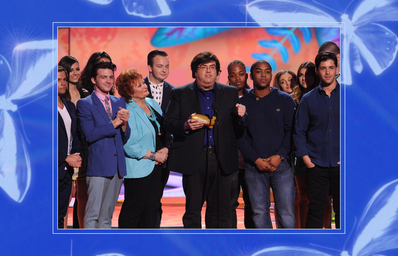 Dan Schneider accepting an award onstage with Nickelodeon stars