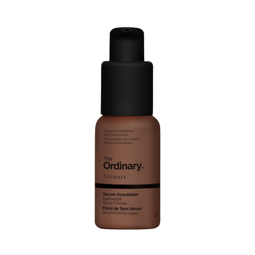 A bottle of serum foundation by The Ordinary, with a sleek black pump top. The matte brown label highlights its lightweight, mindful color formulation.