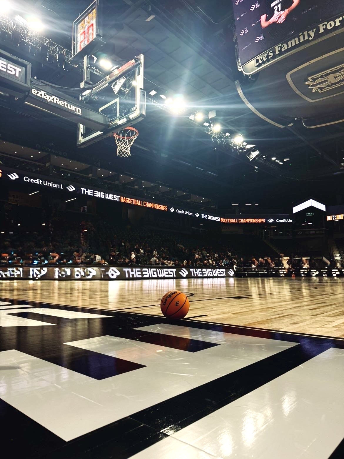 Basketball on the floor in a basketball stadium.