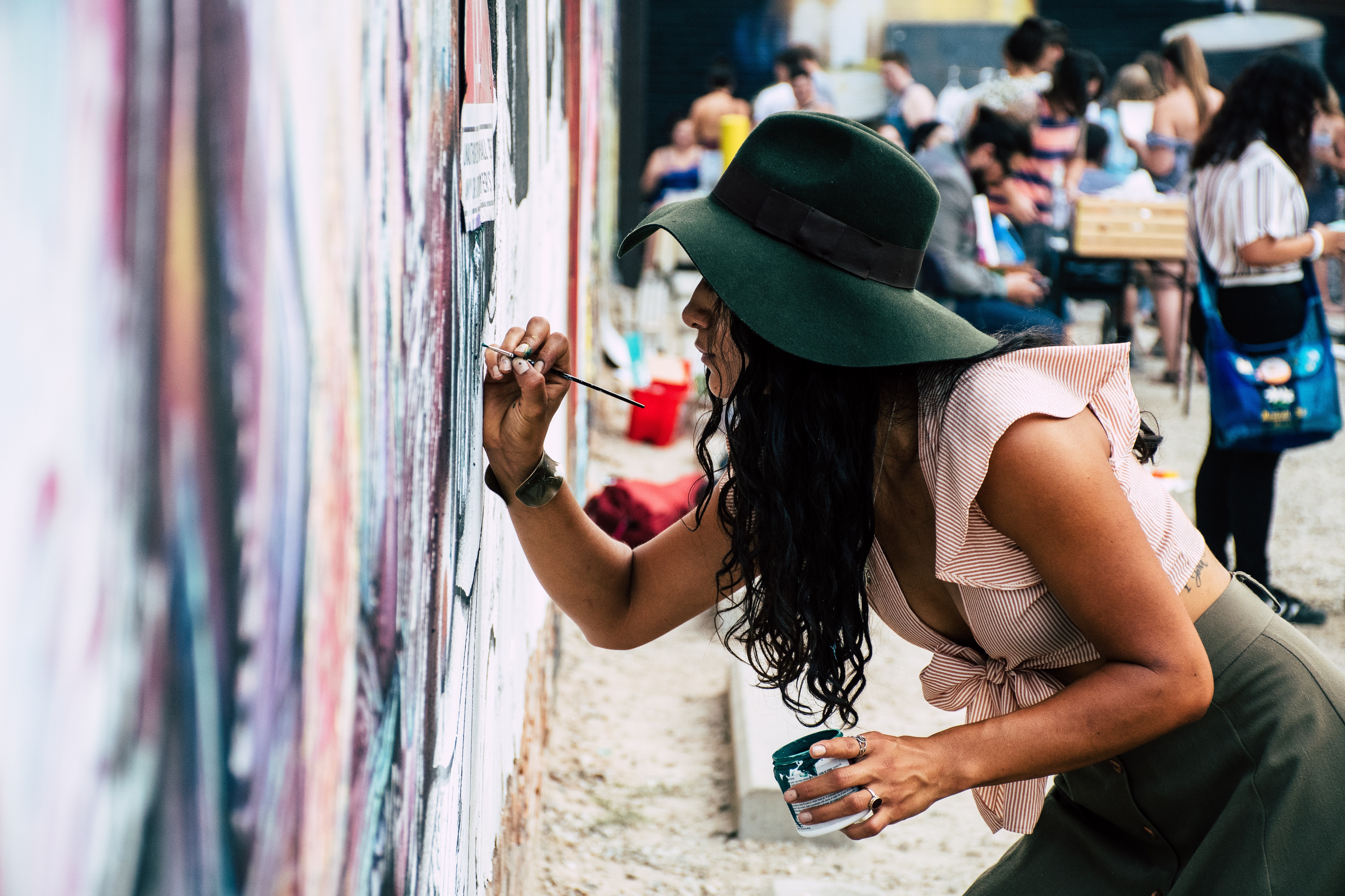 girl in hat painting on a wall