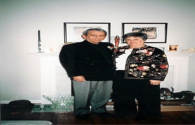 Author\'s grandparents dressed up standing in front of their fireplace in their living room