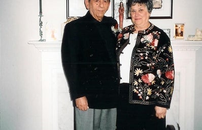 Author\'s grandparents dressed up standing in front of their fireplace in their living room