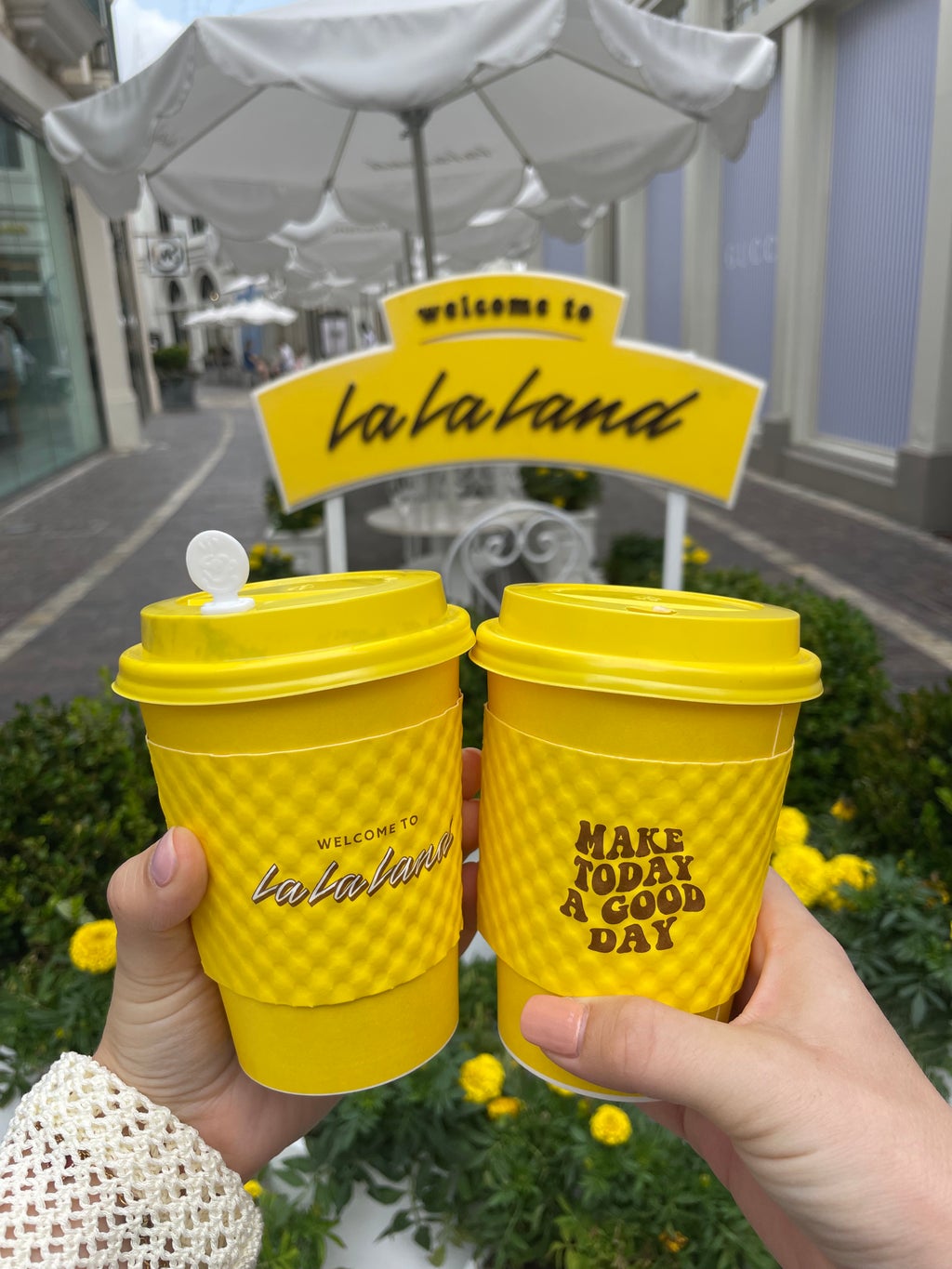 hands holding yellow la la land coffee cups