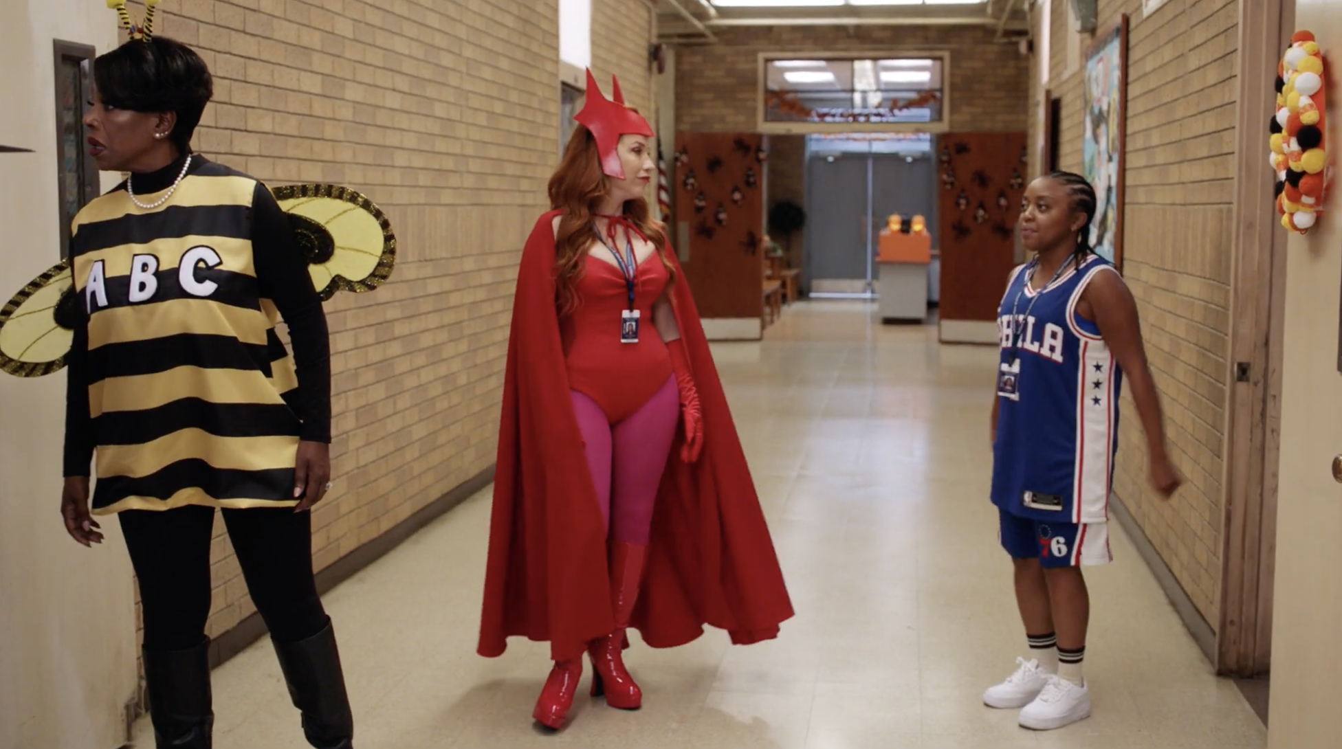 3 women standing in a school hallway with Halloween costumes on.