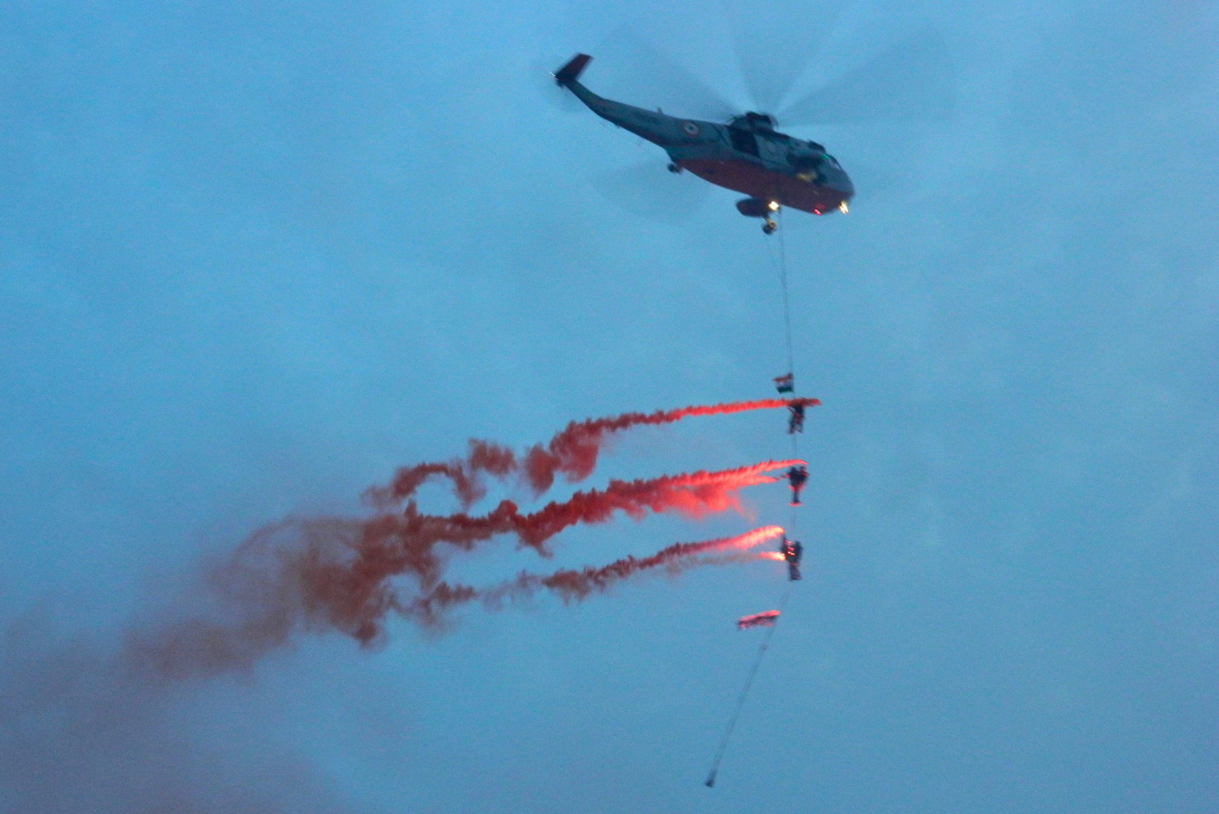 Marine commandos hanging from helicopter with flares during a showcase.