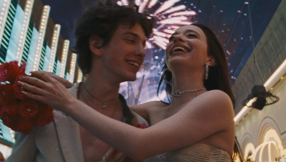 A man (Mark Eidelshtein) and a woman (Mikey Madison) standing with fireworks in the background still image from \