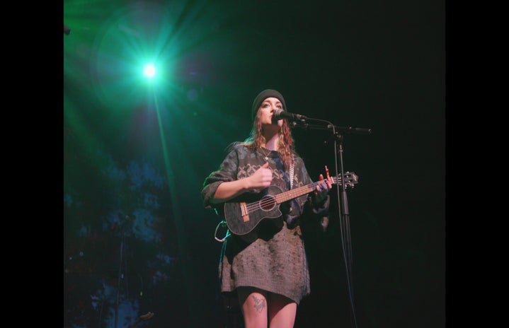 Woman playing ukelele on stage under green lights