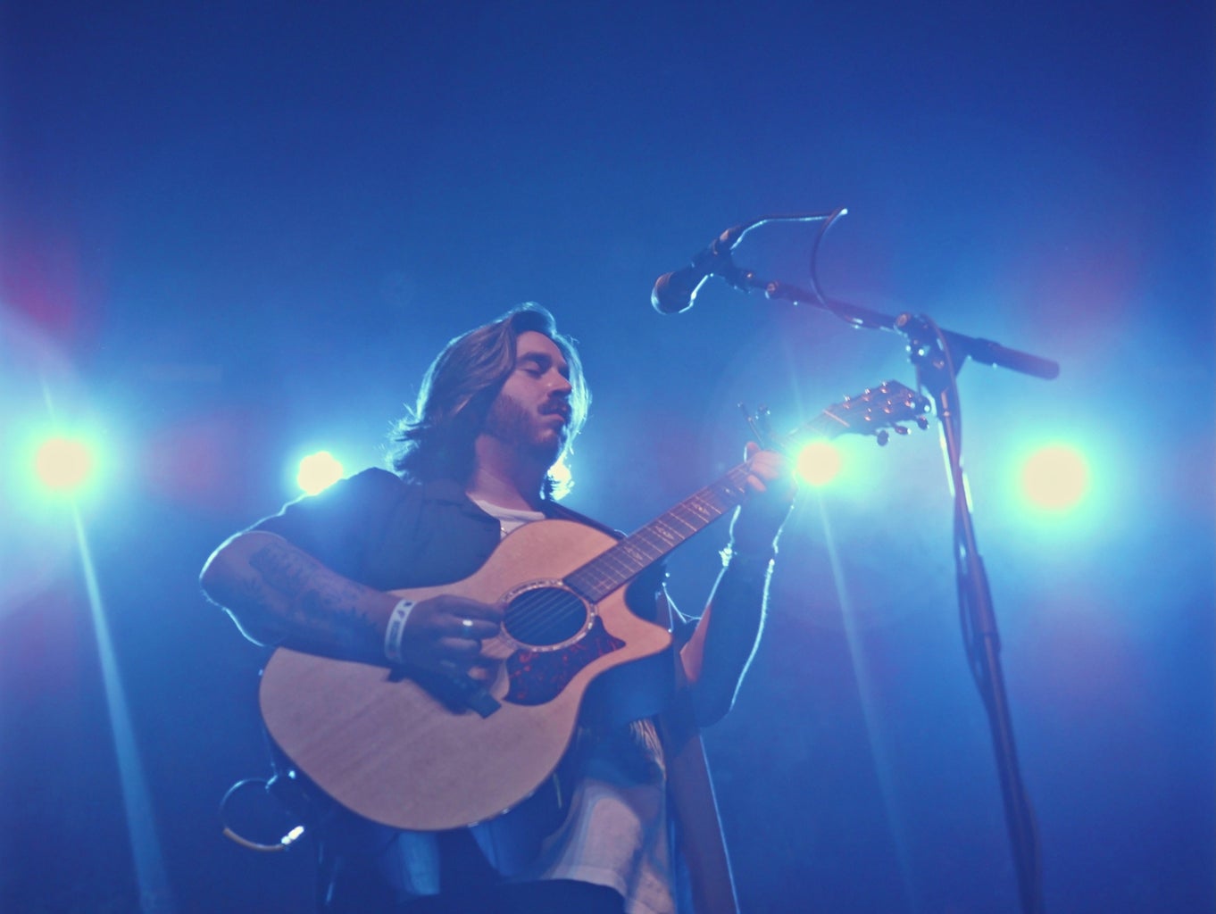 man playing guitar on stage under blue light