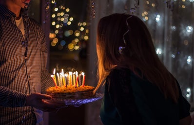 woman being given birthday cake with candles