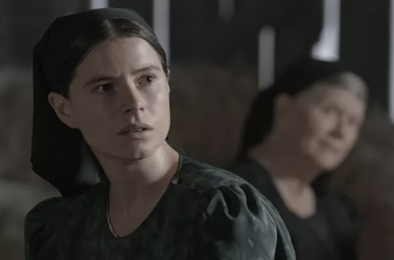 Woman in colony clothing staring into the distance.