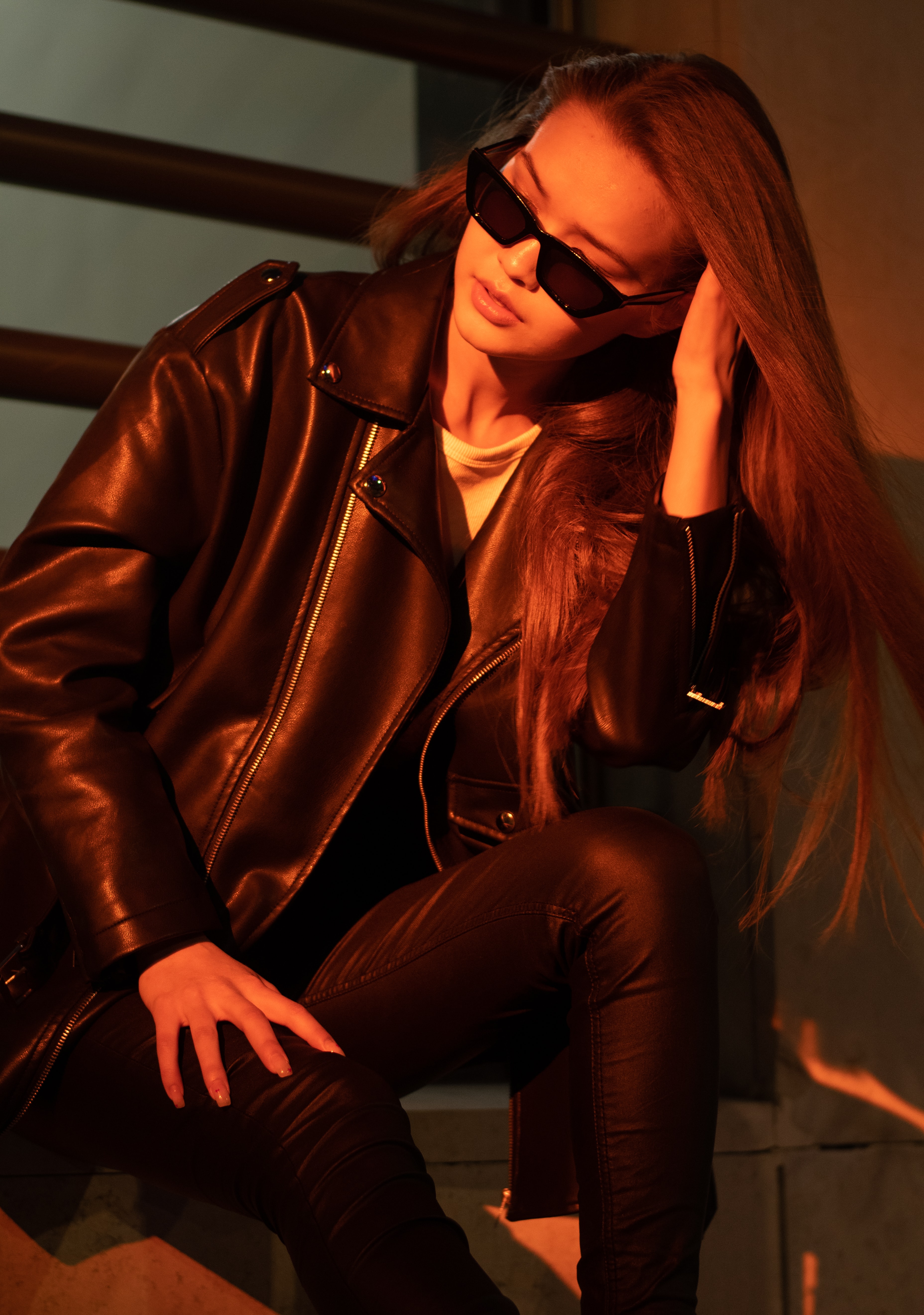 Woman with black sunglasses on and leather jacket.