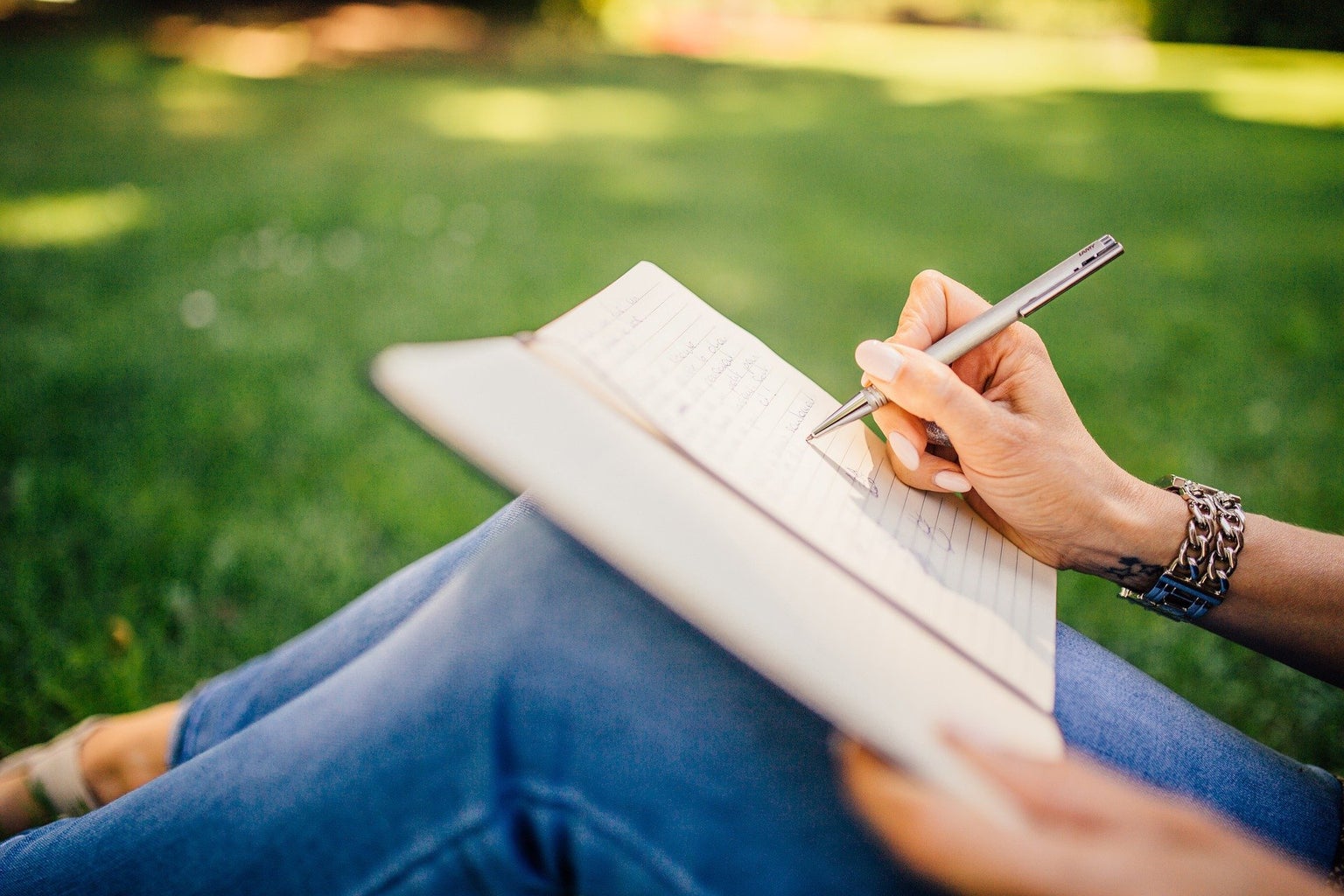 person writing outside in notebook