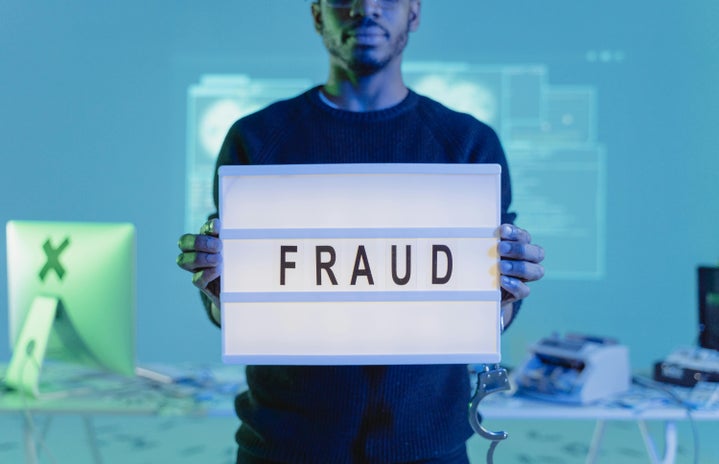 Man holding a sign reading \"fraud\"