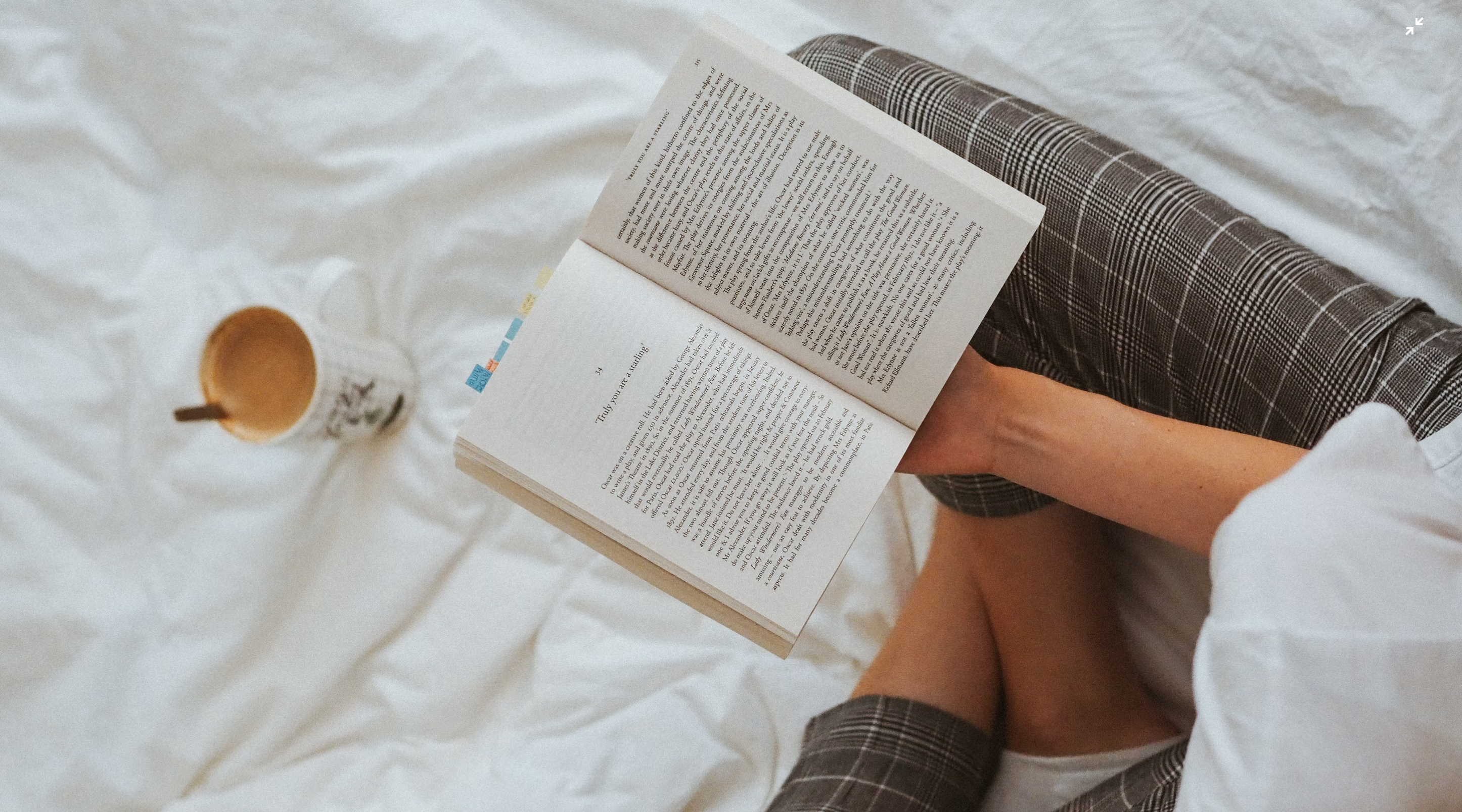 Person holding a book while drinking coffee