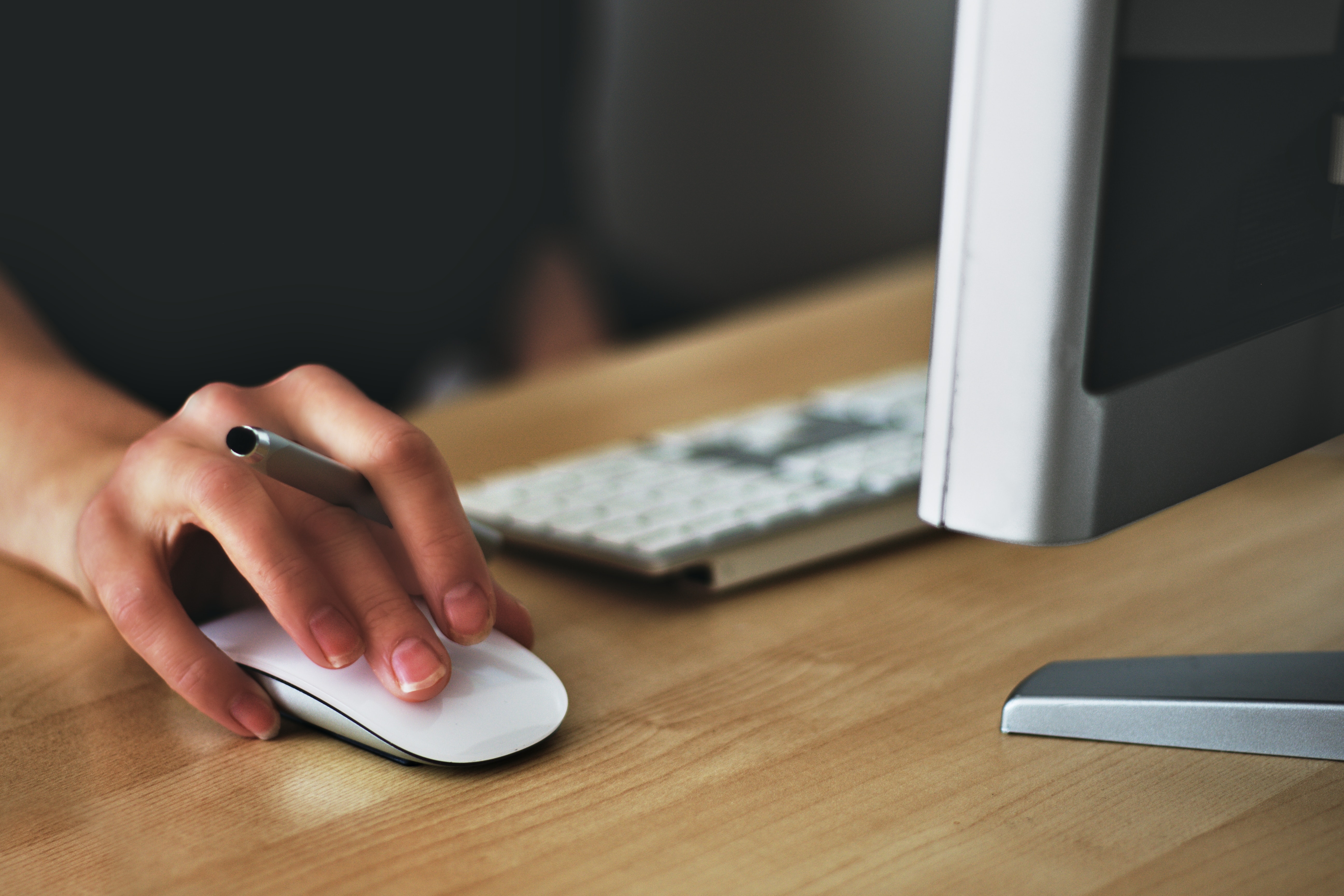 person at desk using computer and mouse
