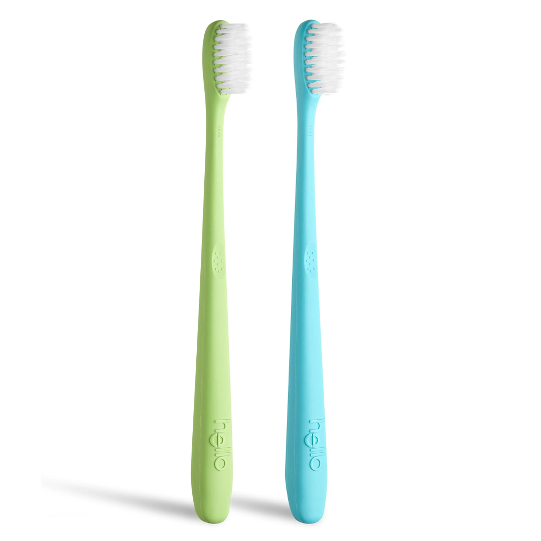 Two slim toothbrushes, one lime green and one turquoise, stand upright on a white background with white bristles, suggesting cleanliness.