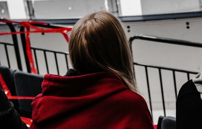 woman in red hoodie sitting on black chair at hockey arena