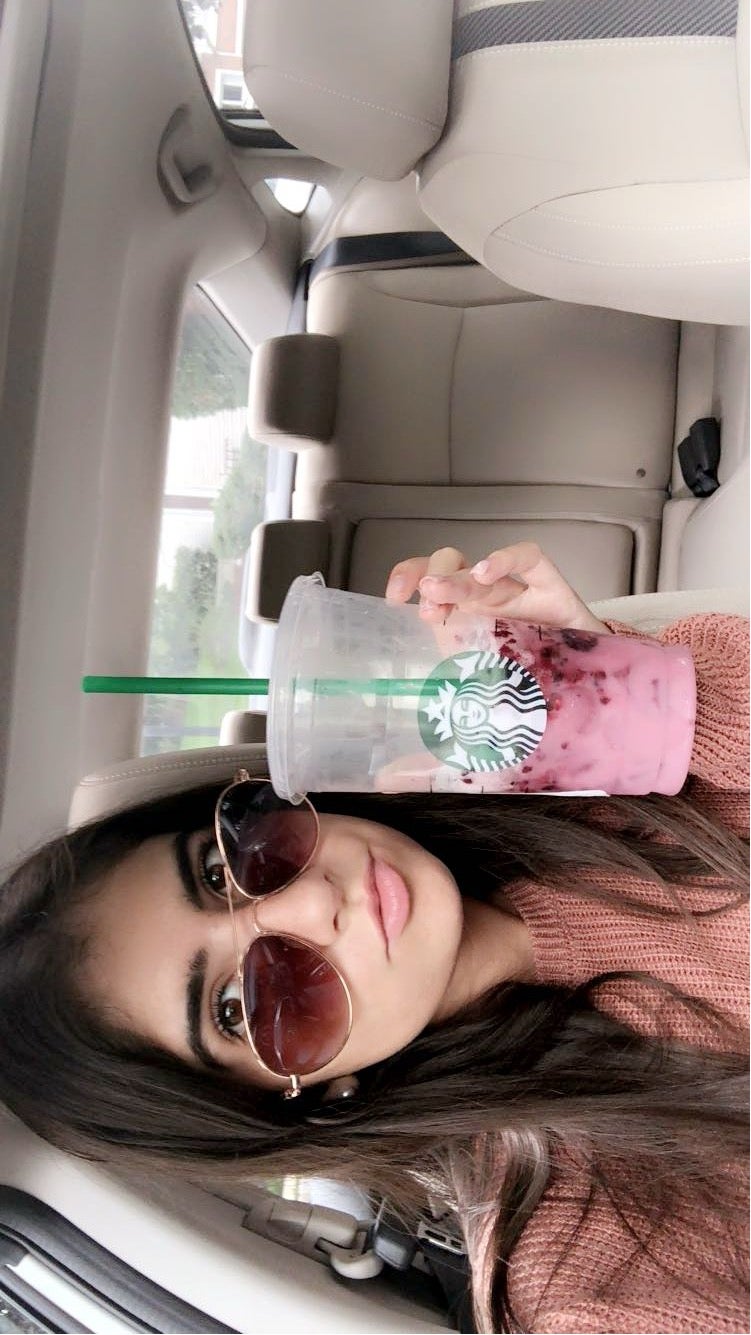 Amanda Ruja holding a Starbucks drink in her car