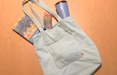 A bird\'s eye view pic of a blue tote bag with a water bottle, claw clip and book.