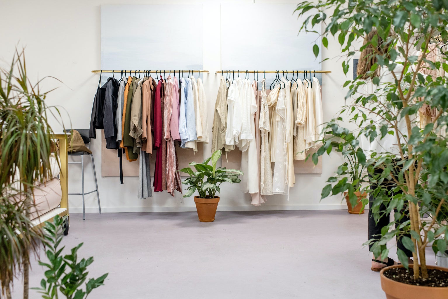 Clothing hangs on a rack with plants on the sides.