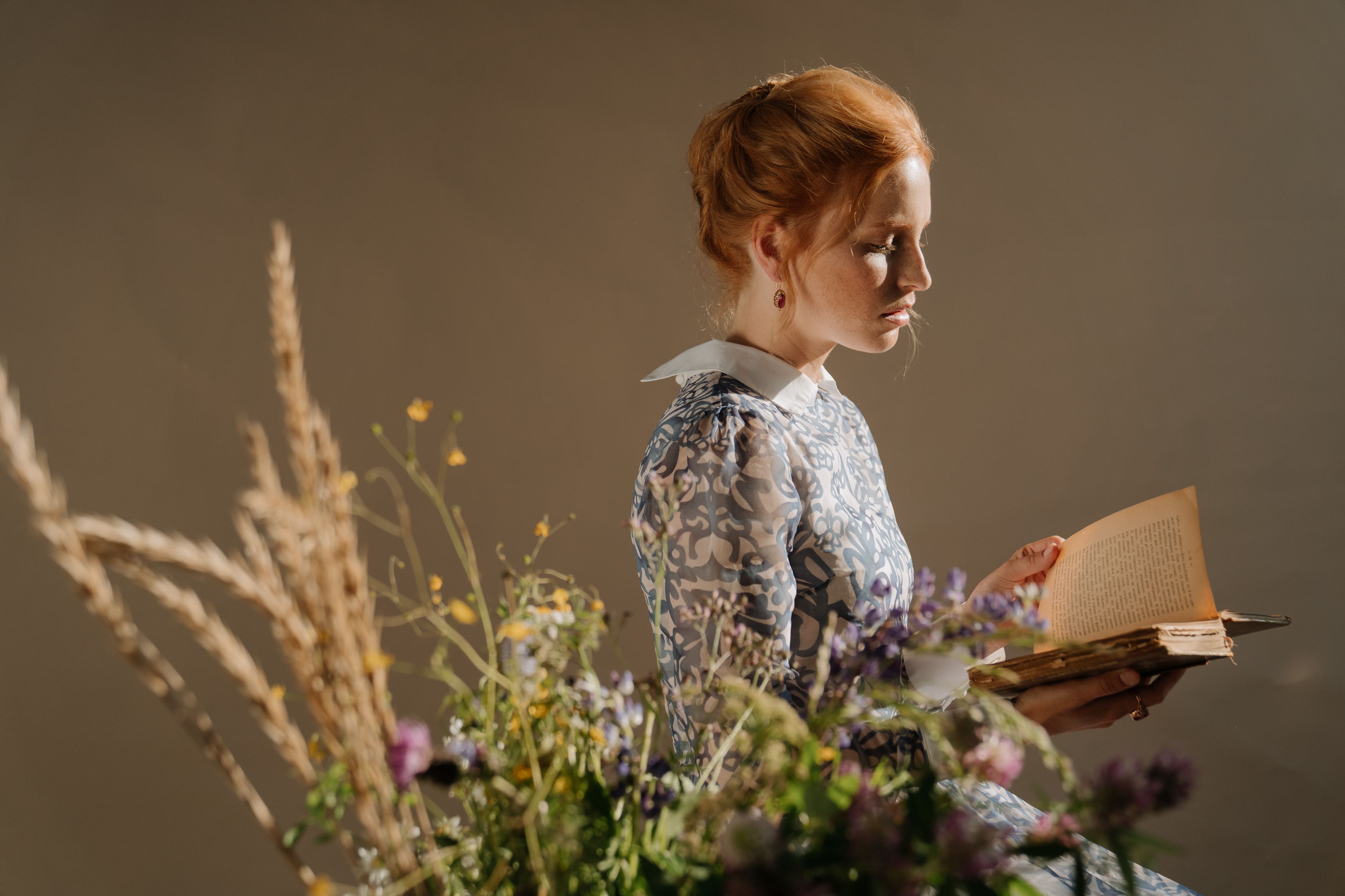 woman reading a book with flowers in front of her