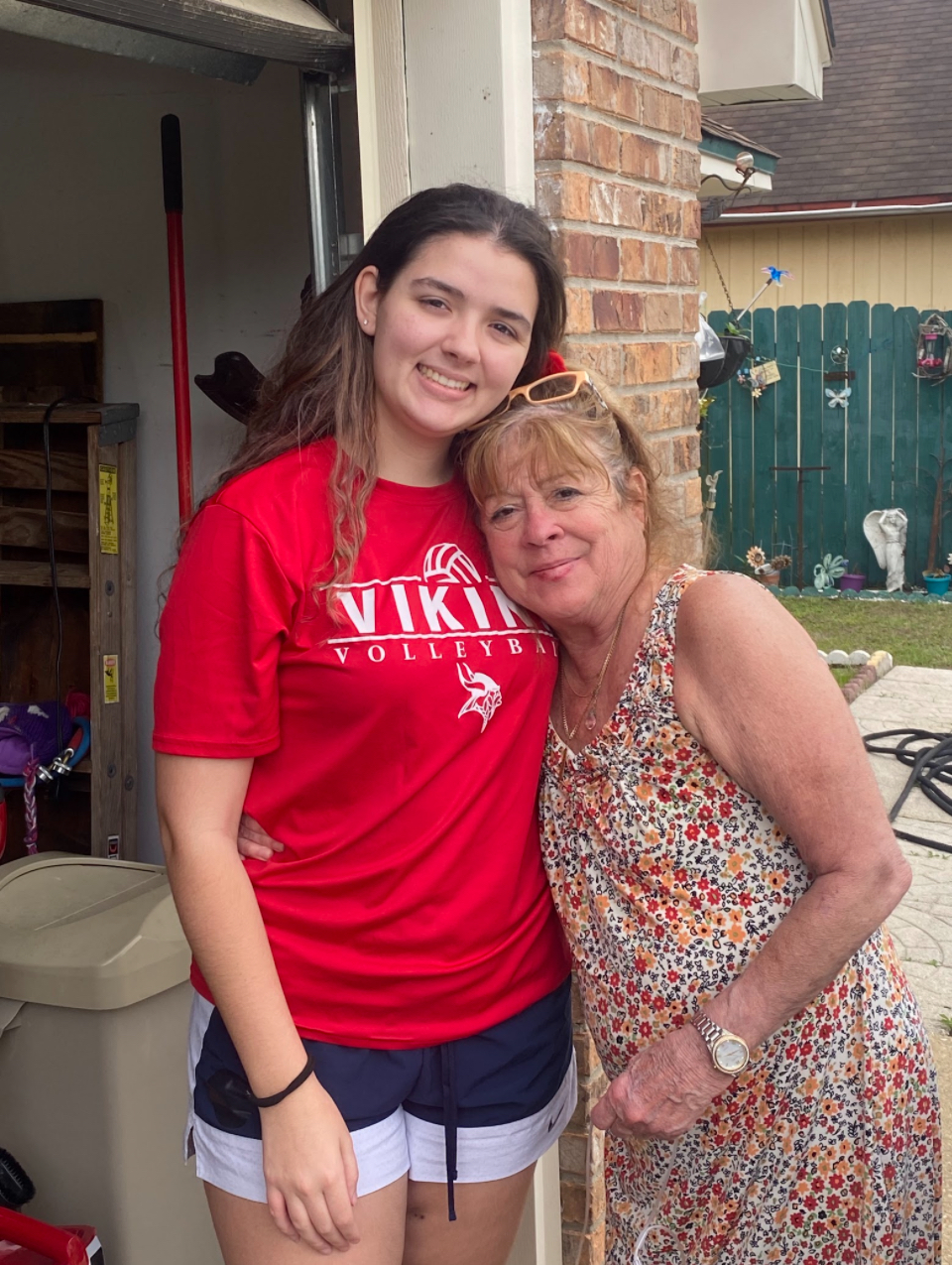 Grandmother standing smiling with granddaughter outside