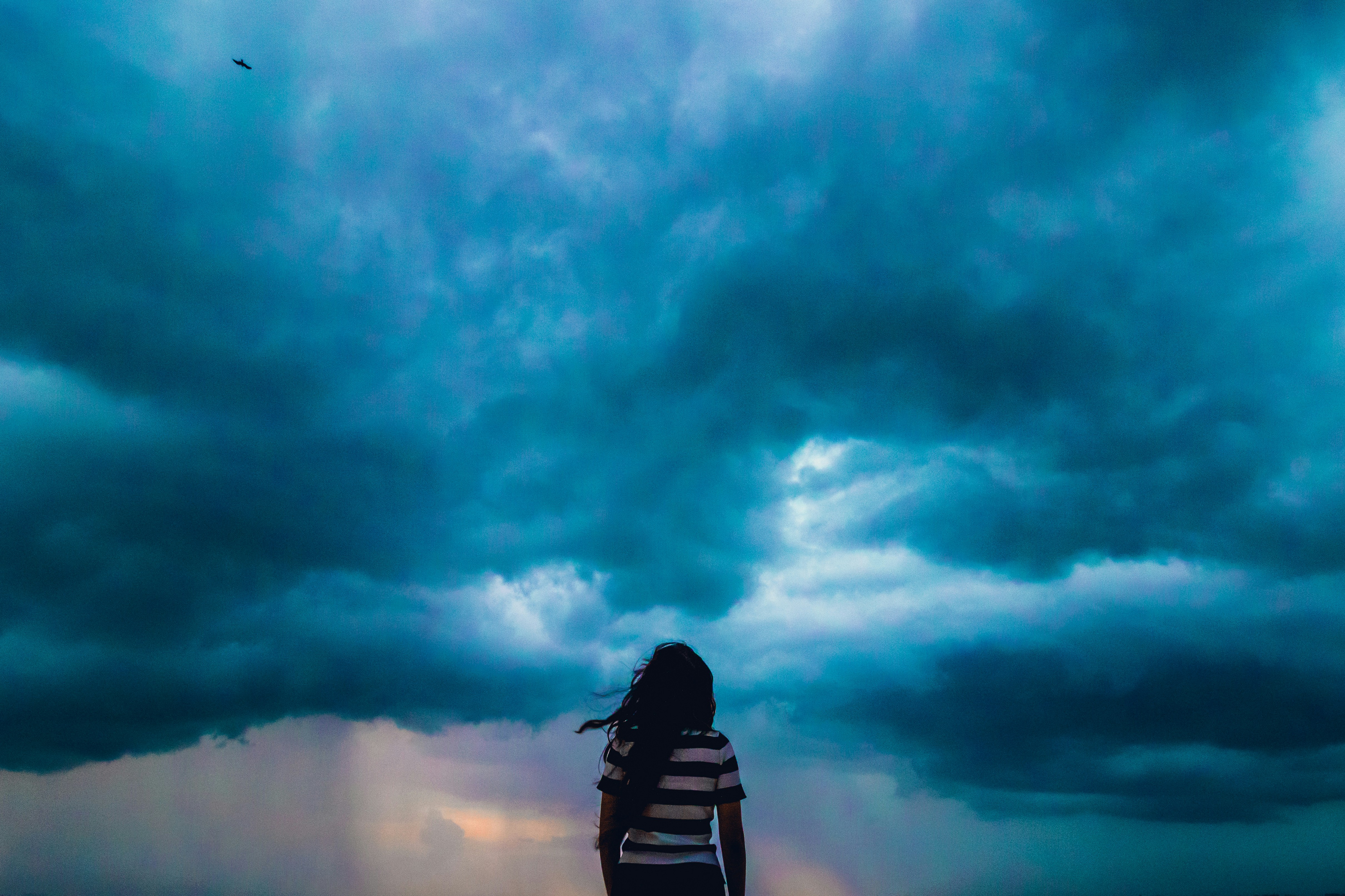 The image is of a girl standing lost in front of dark blue storm.