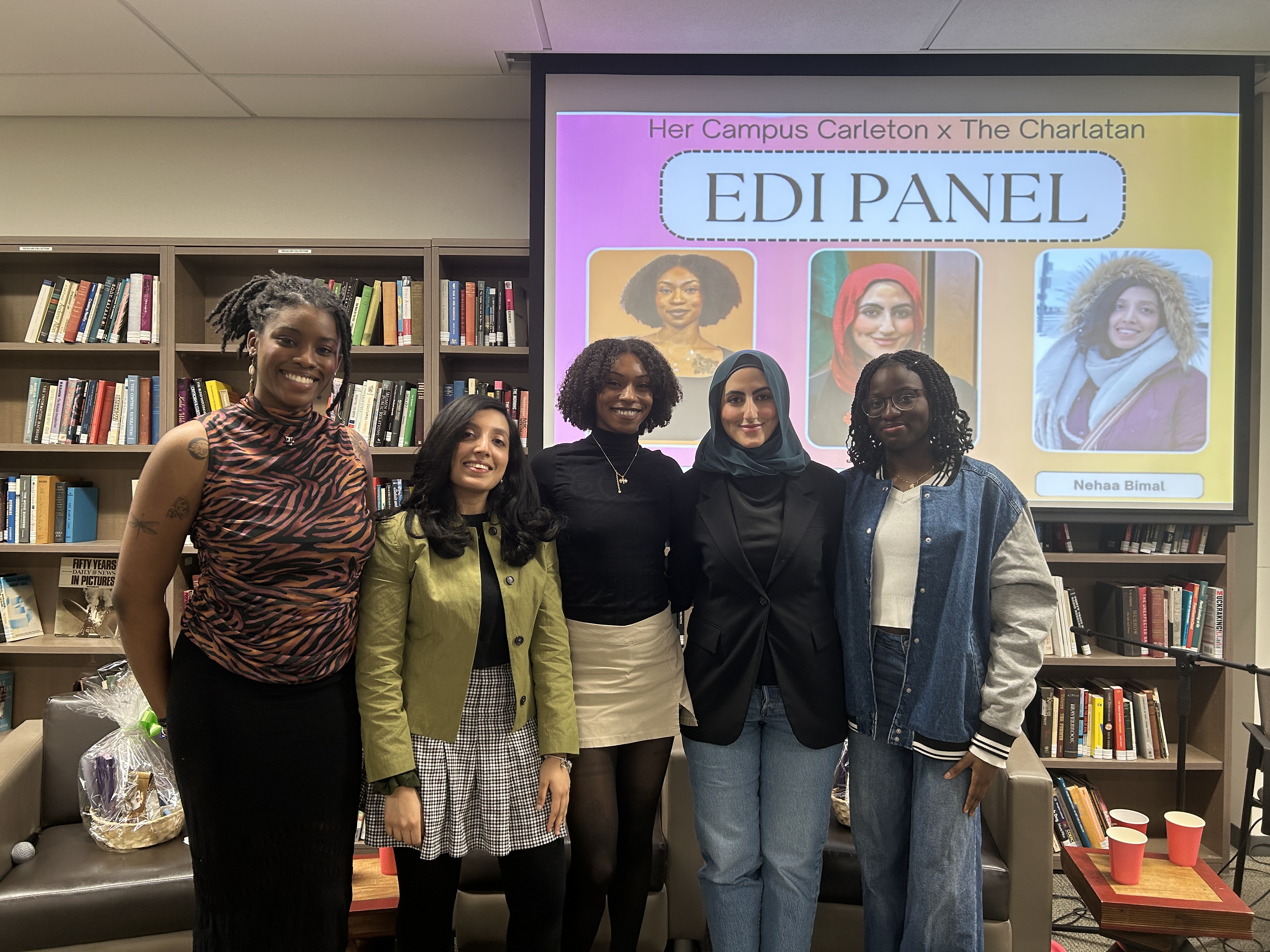 Five women standing in front of a bookshelf and slideshow that says \"EDI Panel\"