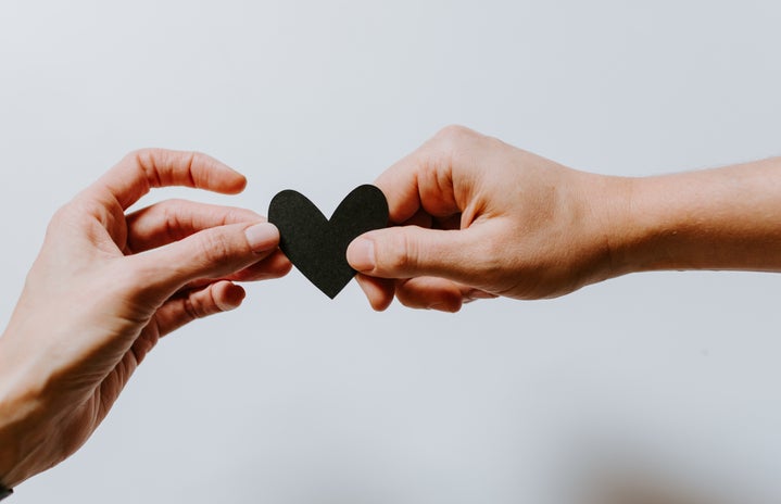 two hands holding tiny black heart