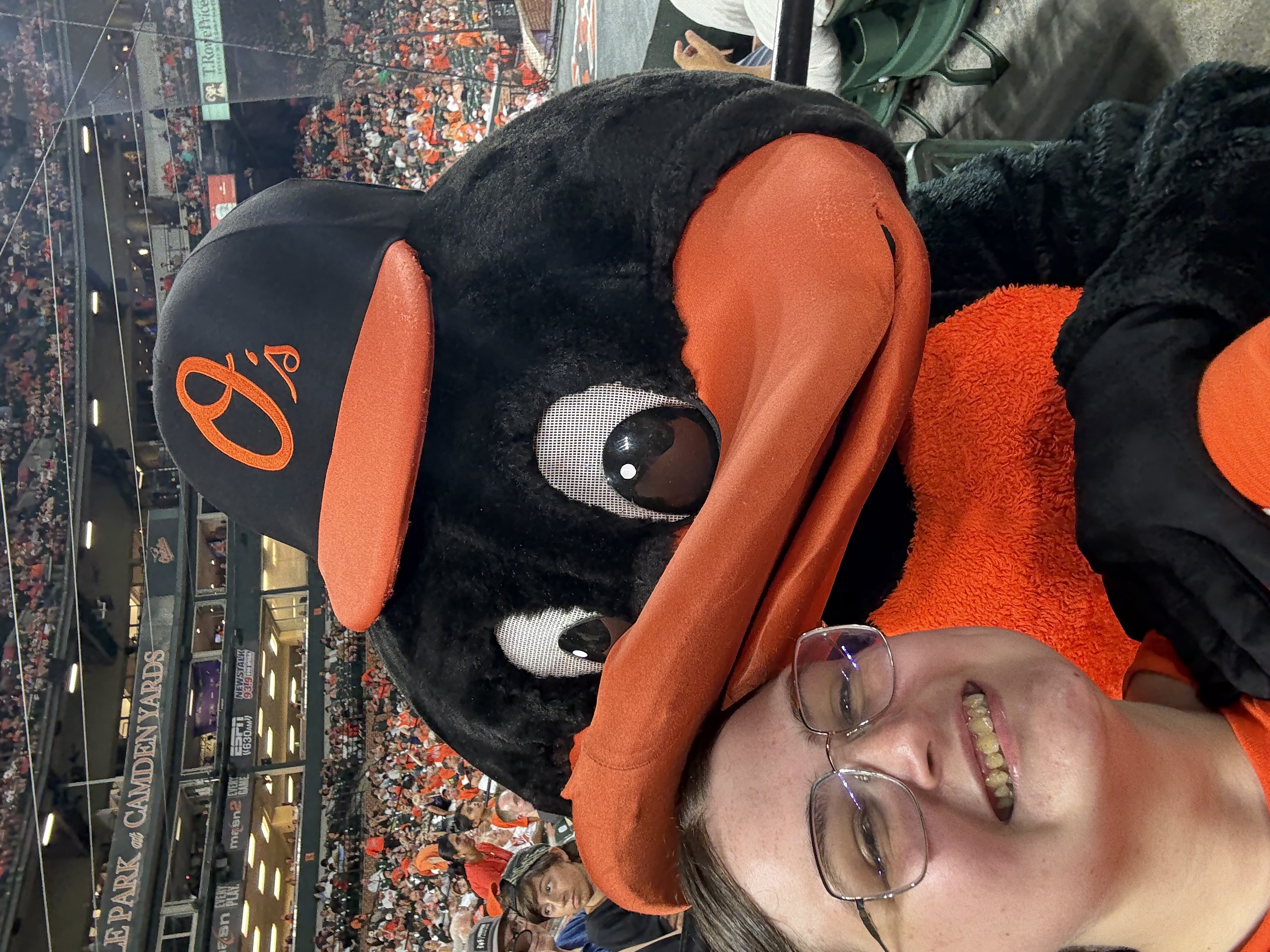 Girl at baseball game with mascot.