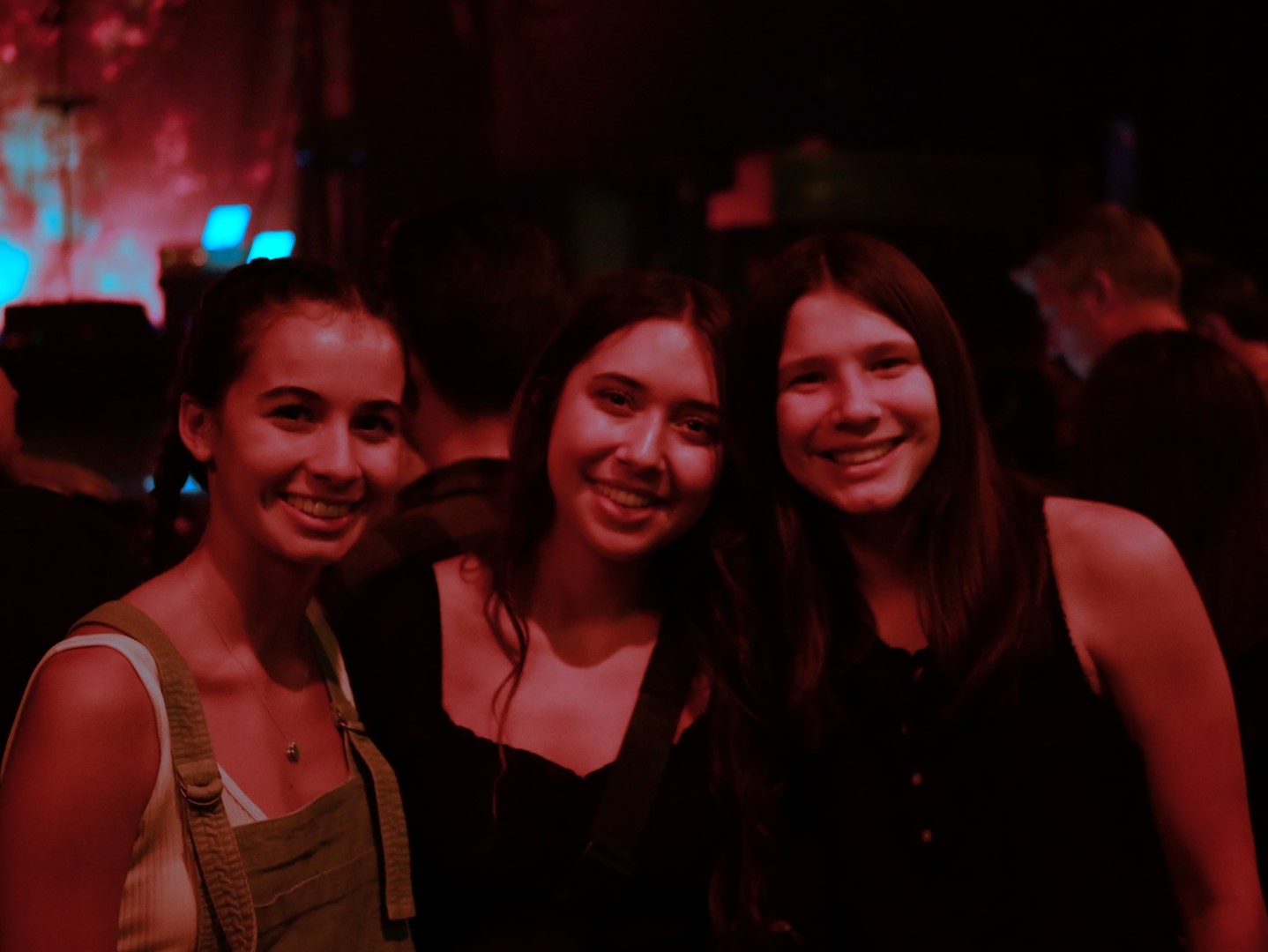 Three girls smile in red lighting