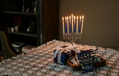 hanukkah blue and white candle with gifts on a table with white tablecloth