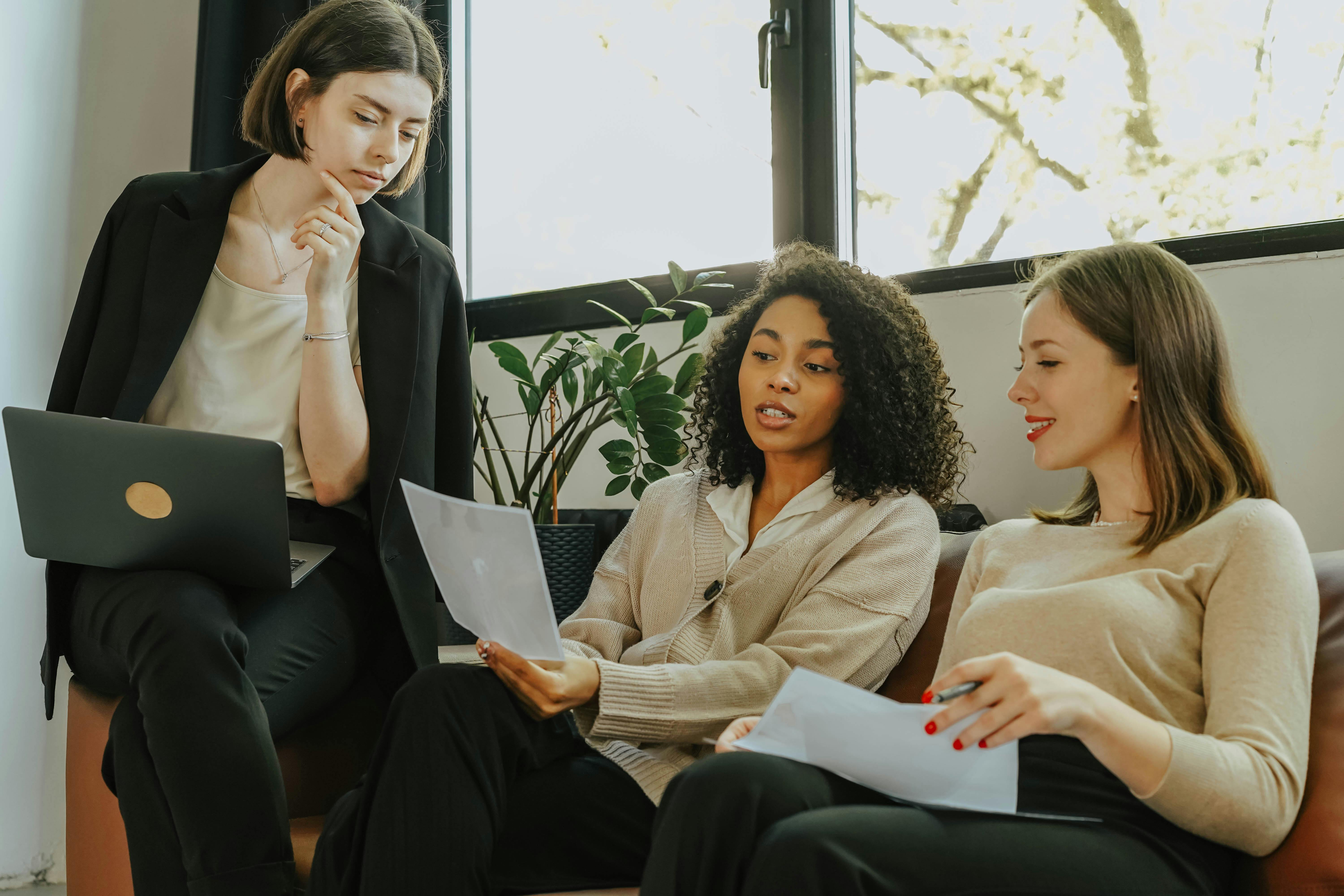 three women on a couch looking a piece of paper