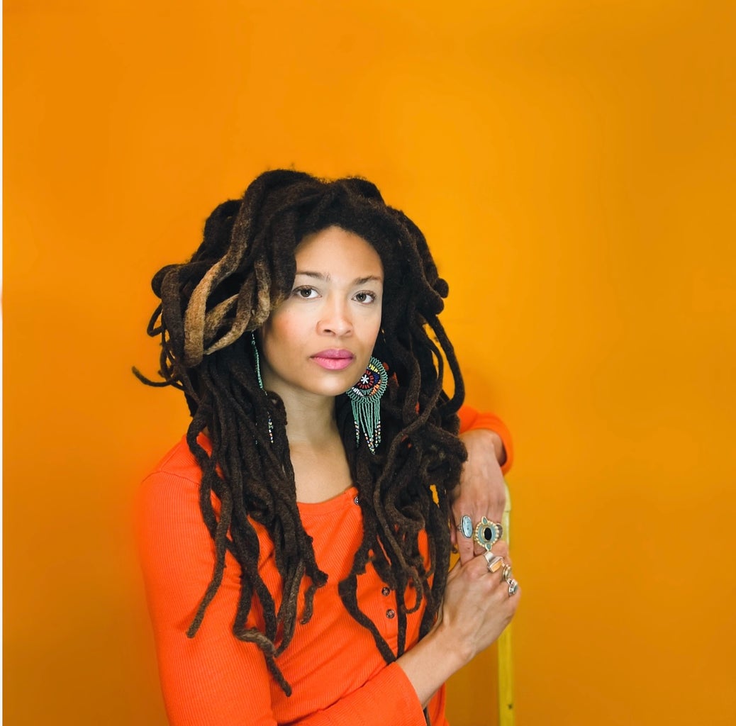 Valerie June posing in front of an orange wall.