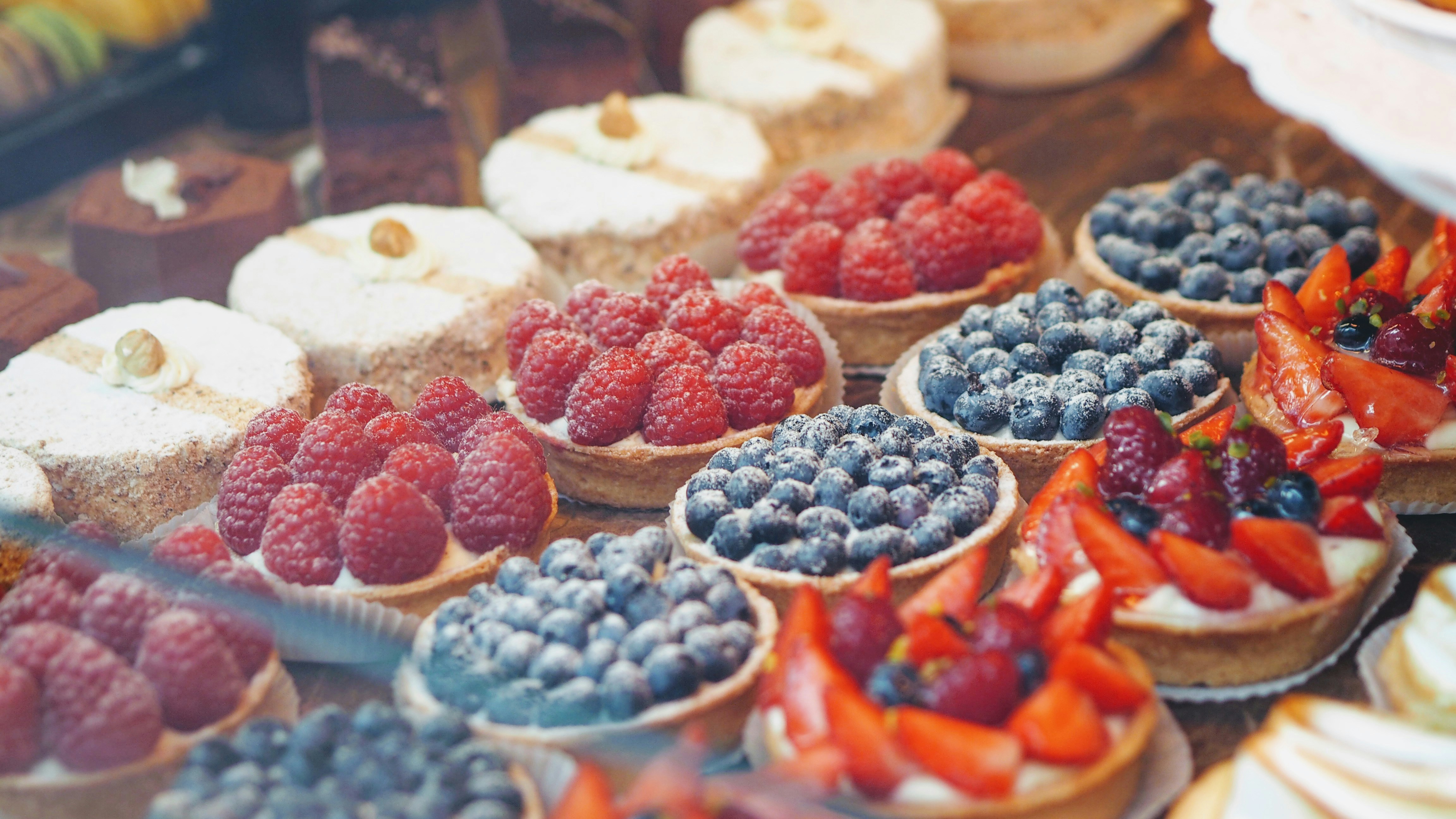 Rows of fruit tarts in a pastry display at a bakery