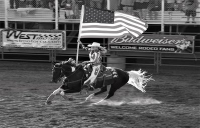 Woman riding a horse carrying an American flag (black and white)