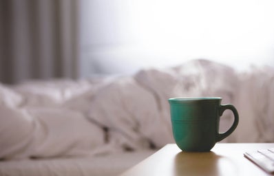 Steaming cup on nighstand by bed