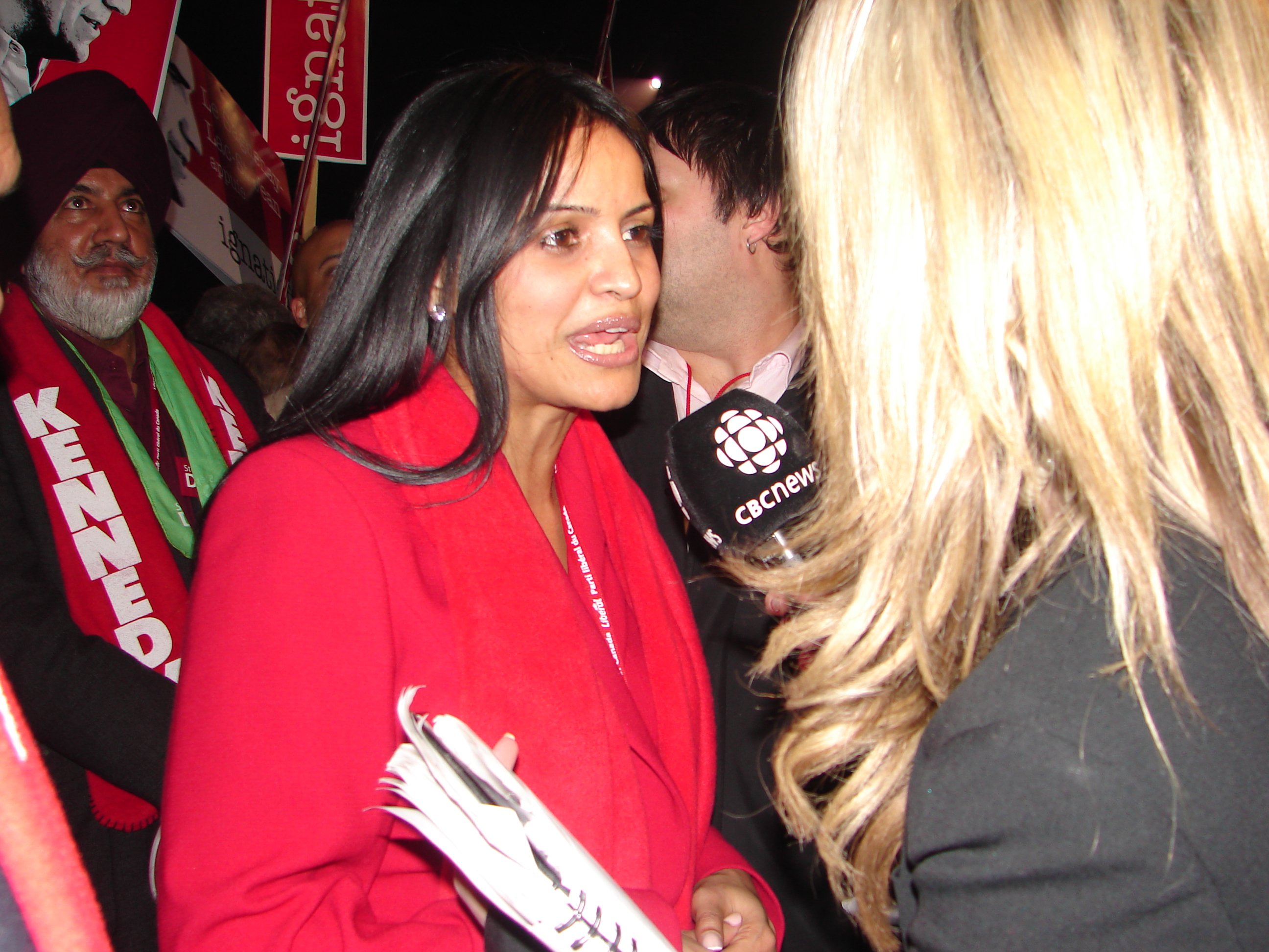 ruby dhalla talking into a microphone, wearing red