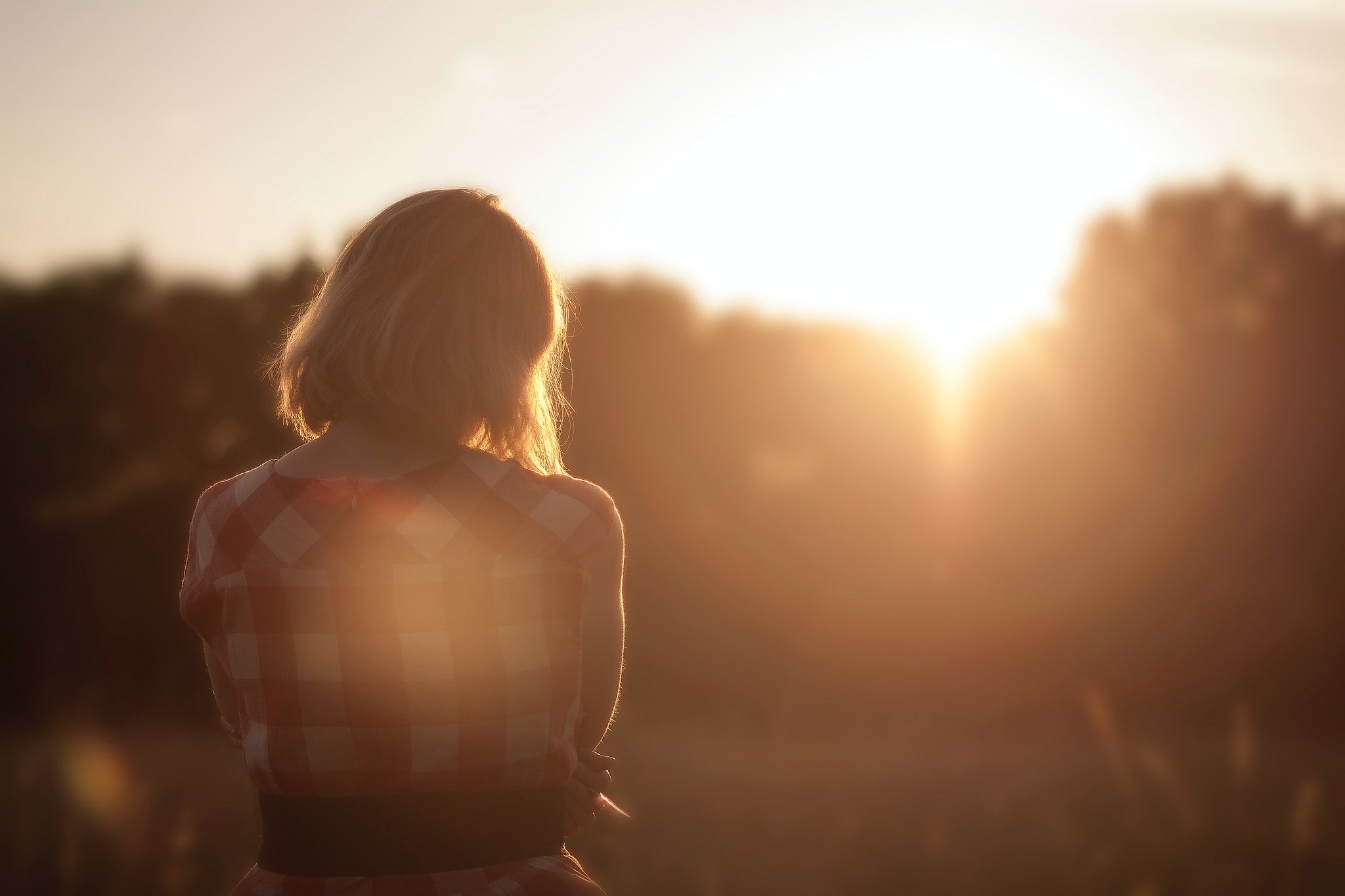 woman looking at the trees in front of the sun